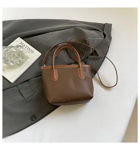 Detail of dark brown lychee textured leather bucket bag on a stylish grey blazer
