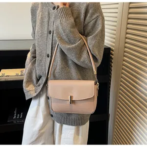 Detail of elegant beige shoulder bag featuring a gold cylindrical metal lock and leather strap