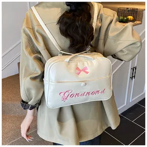 Detail of cream PU leather backpack with pink bow embroidery and cursive text detail