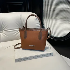 Caramel pebble leather bucket bag with silver metal logo and dual handle straps