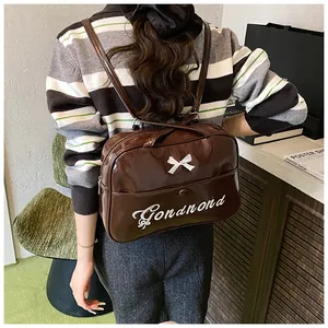 Detail of dark brown glossy backpack with a white bow and embroidered logo on the back