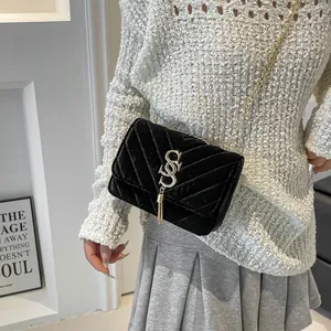 Sac bandoulière en velours noir matelassé avec chaîne dorée et pompon élégant