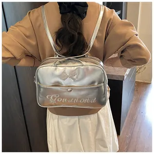Detail of silver metallic backpack featuring a ribbon bow and Gonandnd white embroidery