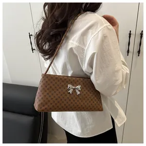 Shoulder bag detail showing brown patterned PU leather and a silver metal bow accent