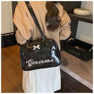 Detail of black glossy patent leather bag with a white 3D bow and logo embroidery