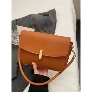 Elegant brown leather crossbody bag with gold buckle on a stylish minimalist background