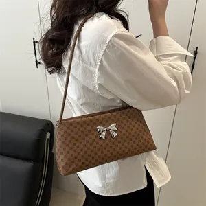 Brown monogram shoulder bag with silver butterfly buckle shown on model in home setting