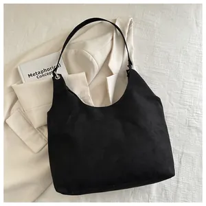 Dettaglio della borsa hobo in camoscio nero con occhielli metallici su sfondo di tessuto bianco