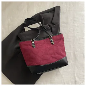 Makroaufnahme der burgunderroten Wildledertasche mit Rautensteppung und Nieten