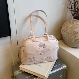 Pink PU leather shoulder bag with silver bow and embroidery on a silver suitcase