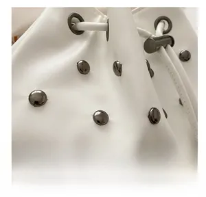 Dettaglio della borsa a secchiello in ecopelle bianca con borchie in metallo grigio
