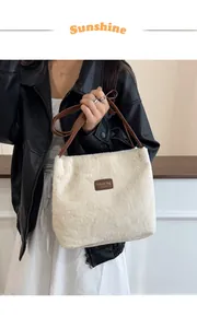 Détail du sac fourre-tout en peluche crème avec écusson tendance et bandoulières marron