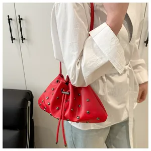 Dettaglio borsa a secchiello rossa con coulisse, rivetti argentati e tracolla sottile