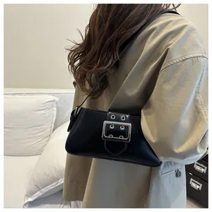 Détail d'un sac à main en cuir noir avec boucle argentée et œillets métalliques réglables