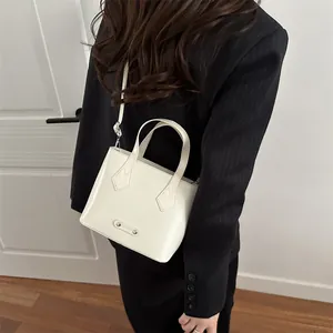 Borsa a secchiello minimalista in vernice bianca con logo in metallo su modella