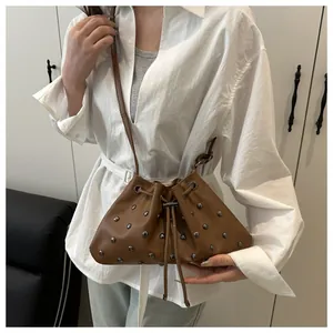Dettaglio di borsa a secchiello marrone con borchie metalliche e chiusura a coulisse