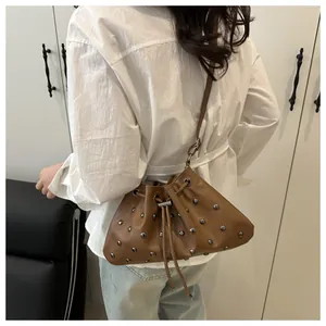 Dettaglio di una borsa a secchiello marrone con borchie argentate e chiusura a coulisse