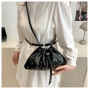 Dettaglio della borsa a secchiello nera con borchie argentate indossata da una modella in posa