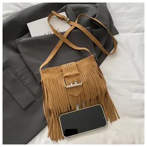 Detailansicht der braunen Wildledertasche mit Fransen und Silberschnalle auf einem Anzug