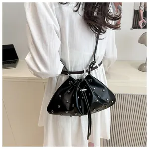 Dettaglio di una borsa a secchiello nera con coulisse, rivetti argentati e tracolla