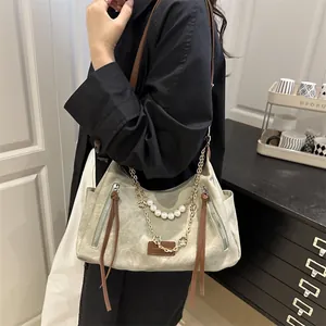 Sac bandoulière gris chic avec perles et chaîne dorée sur un mannequin