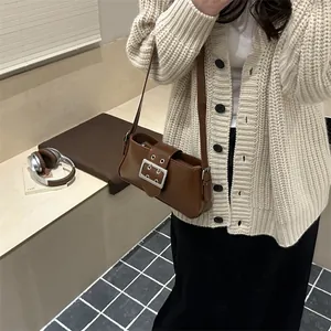 Sac baguette vintage marron en similicuir avec boucle argentée porté par un mannequin
