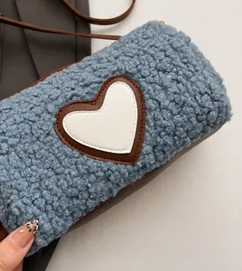 Detail of blue faux shearling mini crossbody bag with a large white heart patch and leather trim