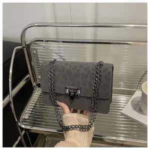 Details der grauen Handtasche mit Leopardenmuster, Metallkette und Schnallenverschluss