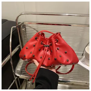 Dettaglio della borsa a secchiello rossa con coulisse, borchie e trama in pelle