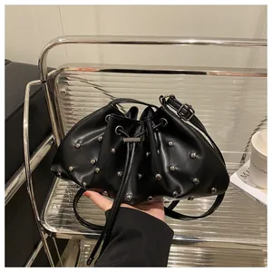 Dettaglio della borsa a secchiello in pelle nera con borchie argento e chiusura a coulisse