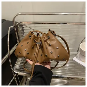 Dettaglio della borsa a secchiello in pelle marrone con borchie e coulisse