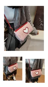 Détail du sac oreiller en peluche rose avec patch coeur rouge et lanière en cuir
