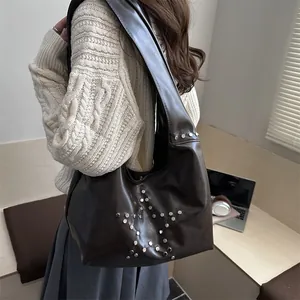Brown leather shoulder bag with silver rivet star pattern shown on a model