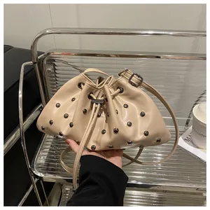 Dettaglio della borsa a secchiello beige con coulisse, borchie argentate e trama a pieghe