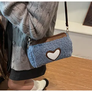 Détail du sac à main en peluche bleu clair avec cœur et finitions en cuir brun