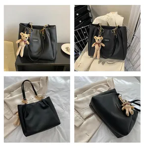 Detail of black tote bag with fashion tag, gold chain handle and bear charm decoration