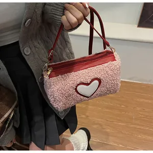 Détail du sac cylindre en polaire rose avec poignées en cuir rouge et broderie cœur