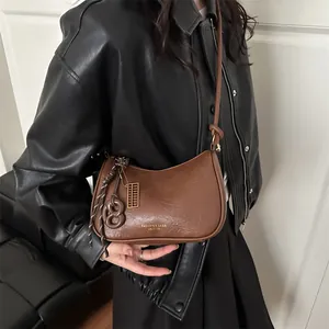 Borsa hobo marrone minimalista con scritte dorate indossata da una modella