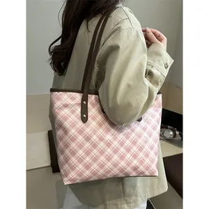 Sac fourre-tout à carreaux rose et blanc avec lanières brunes porté par un mannequin