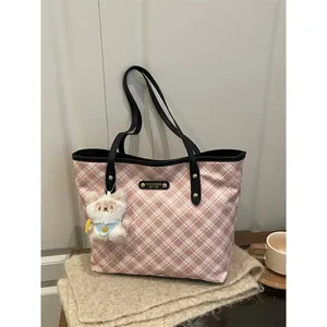 Sac fourre-tout à carreaux rose et blanc avec breloque ours sur une table en bois