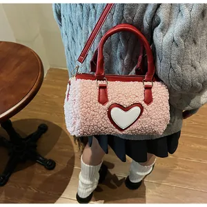 Détail du sac Boston en peluche rose avec patch cœur rouge et lanières en cuir