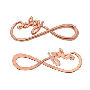 Detailed close-up of infinity symbol charms featuring baby script in rose gold finish