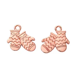 Macro detail of rose gold Christmas glove charms with bow relief and textured metal finish