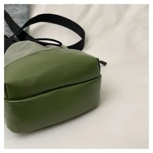 Close-up of green drawstring bucket bag featuring nylon and synthetic leather patchwork