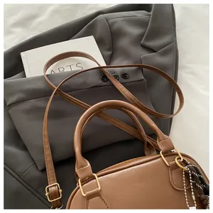 Détail d'un sac boston en cuir marron avec dorures et pendentif ruban rayé décoratif
