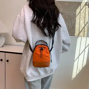Orange and brown drawstring crossbody bag with adjustable strap worn by a model