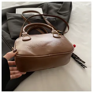 Détail du sac bowling marron vintage avec lettres embossées et un pendentif à franges