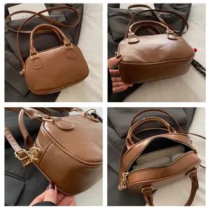 Vue macro du sac Boston en cuir PU marron avec texte gaufré et détails en métal doré
