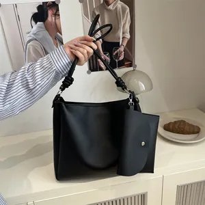 Chic black matte leather tote bag with unique knotted shoulder strap and matching pouch