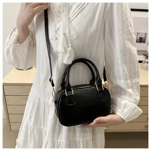 Détail d'un sac bowling en cuir noir mat montrant la finition texturée et les boucles dorées